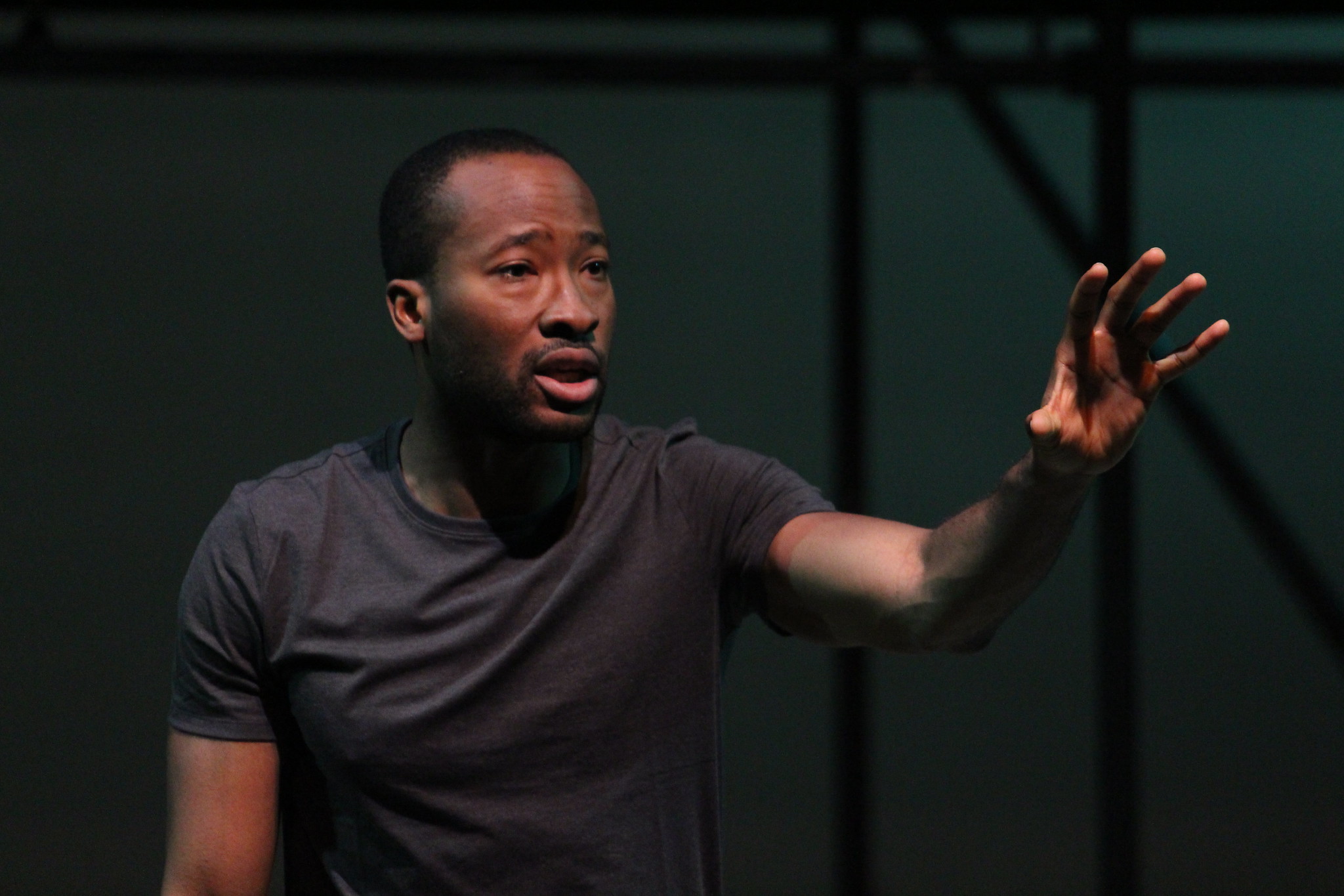 a black man on stage reaches his arm out to the right