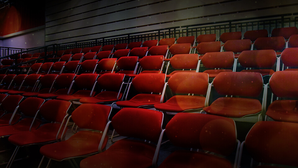A row of empty red theater chairs