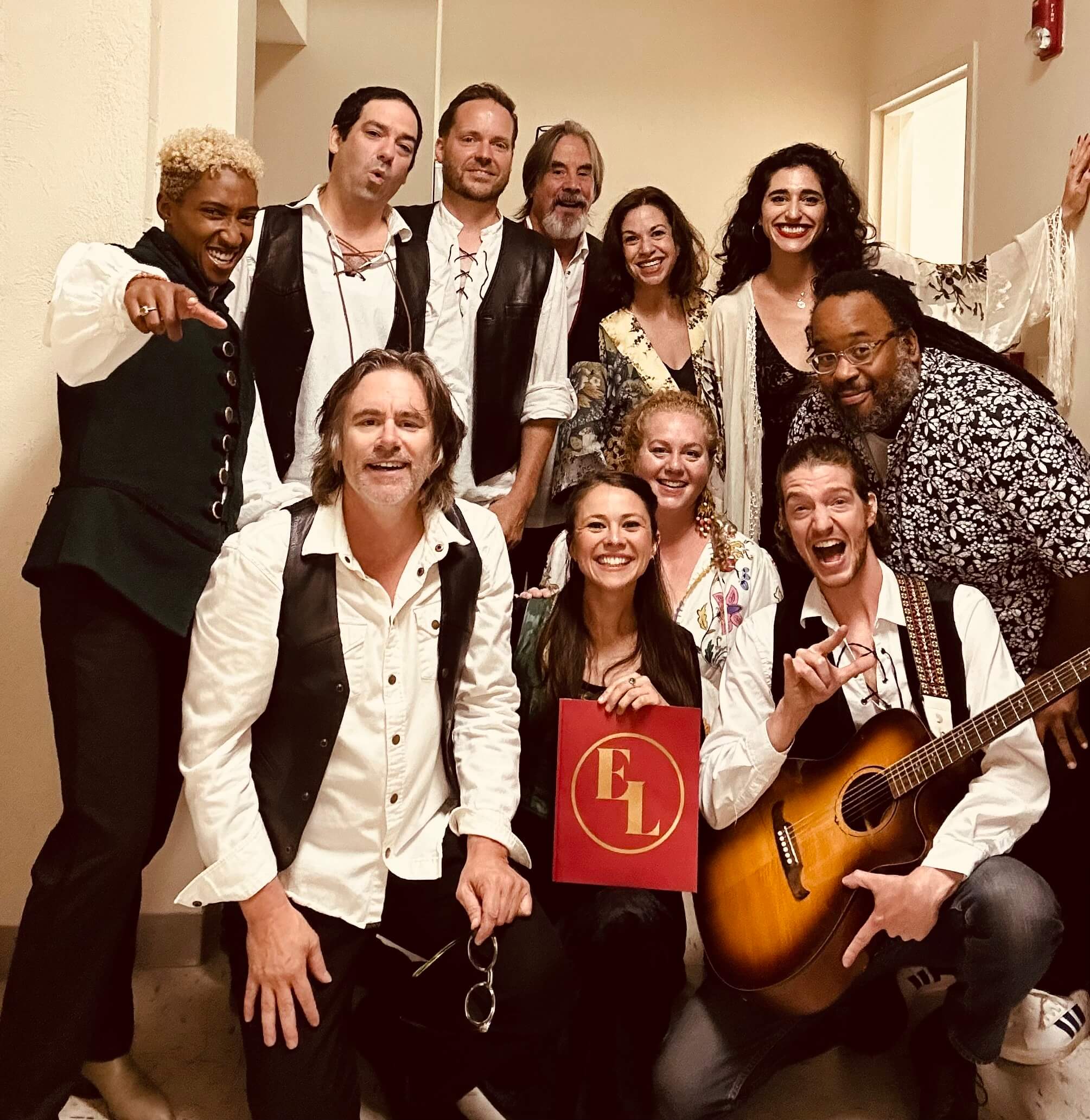 A group of musicians in black and white costumes pose for a photo in a hallway