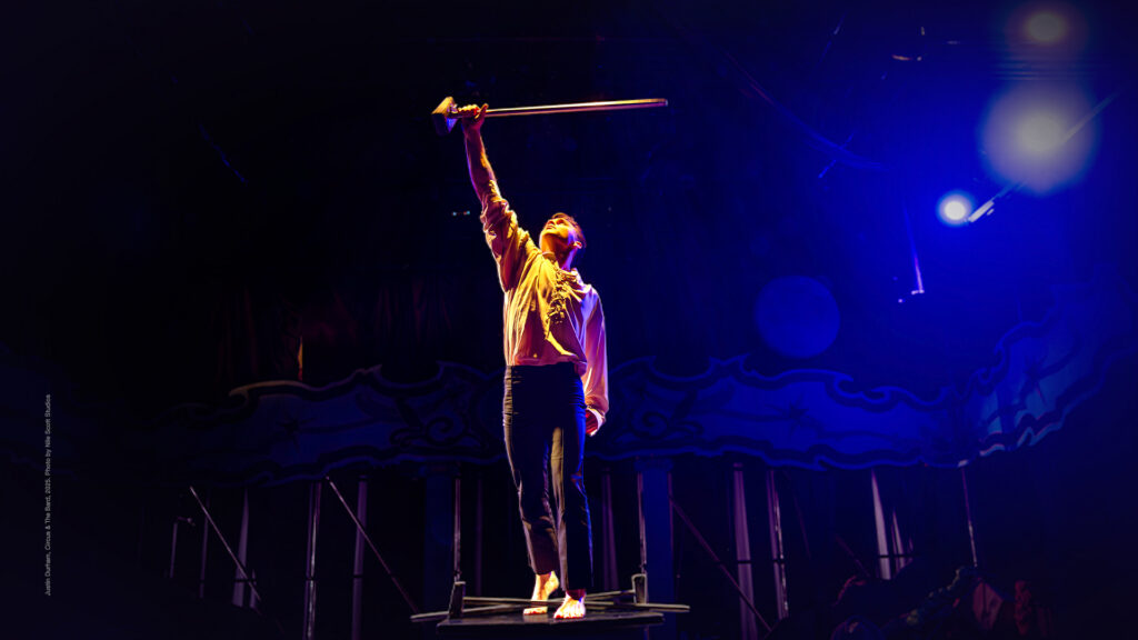 a man holds a wooden stick over his head like a sword